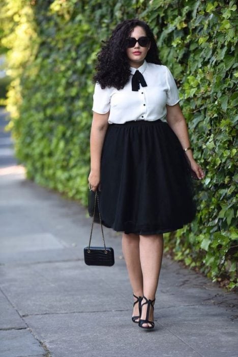 Chica curvy usando camisa blanca y falda negra en línea A, con tacones negros