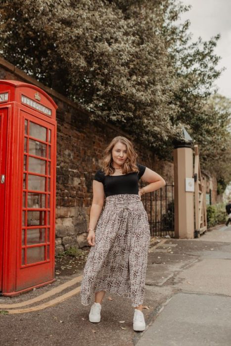 Chica curvy usando maxi falda de estampado con blusa negra ajustada