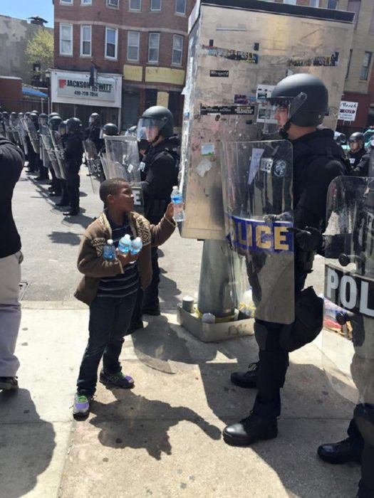 Niño entrega botellas de agua a policías que llevan horas bajo el sol