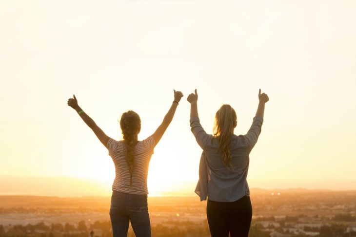 Amigas en la cima de una montaña disfrutando del atardecer