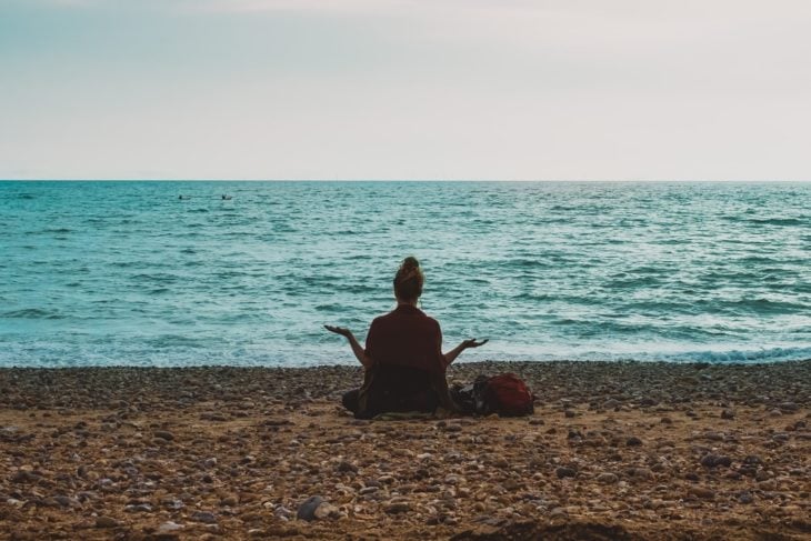 Chica meditando frente al mar