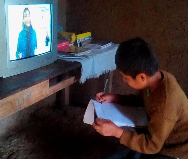 Niño tomando clases a distancia por medio de una televisión