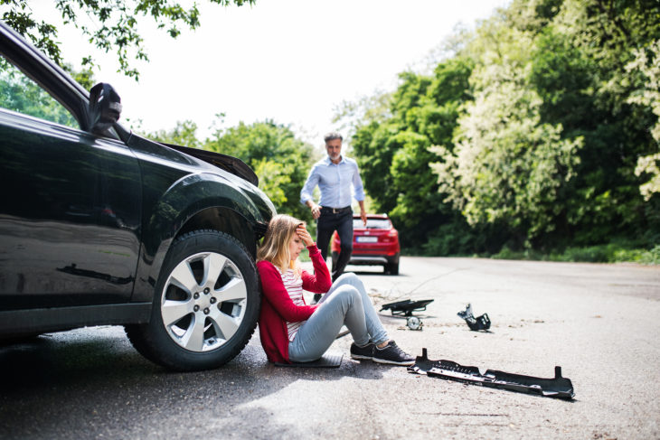 Chica sentada en el piso después de haber tenido una accidente automovilístico