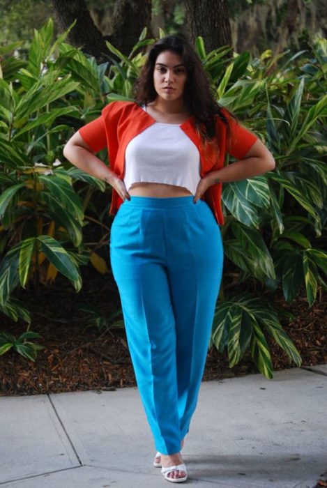 Chica curvy usando pantalón azul, top blanco y saco color rojo, con tacones