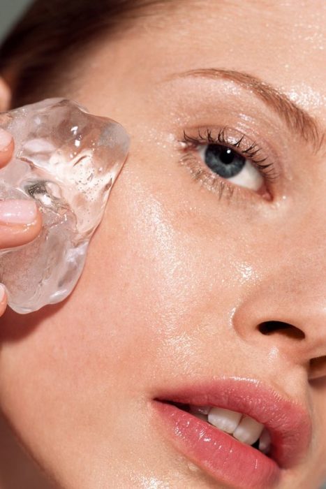 Chica frotando un hielo sobre su rostro limpio