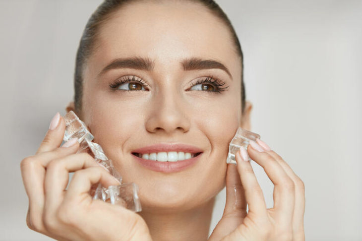 Chica frotando hielos sobre su rostro como terapia facial