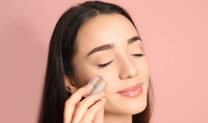 Chica limpiando su rostro con un cubo de hielo