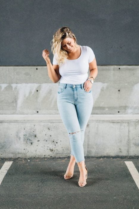 Chica curvy usando tacones, jeans claros y blusa blanca