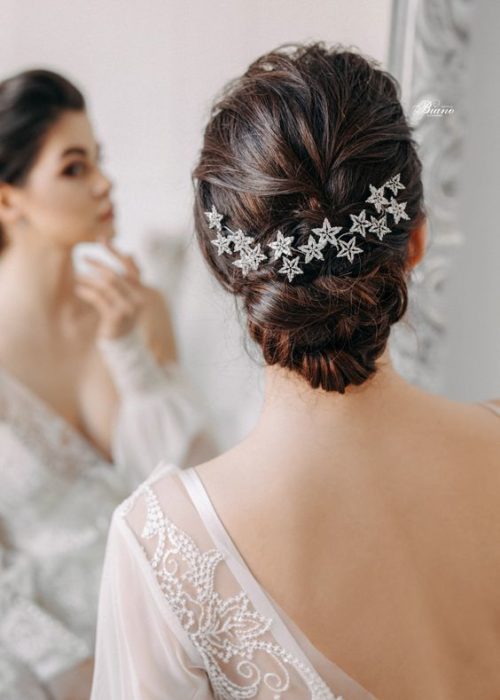 Chica de cabello oscuro agarrado en un chongo con broches de estrella