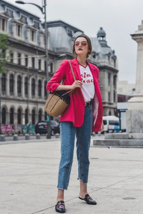 Chica usando blazer de color rosa fucsia y blusa blanca, con pantalon denim y mules negros