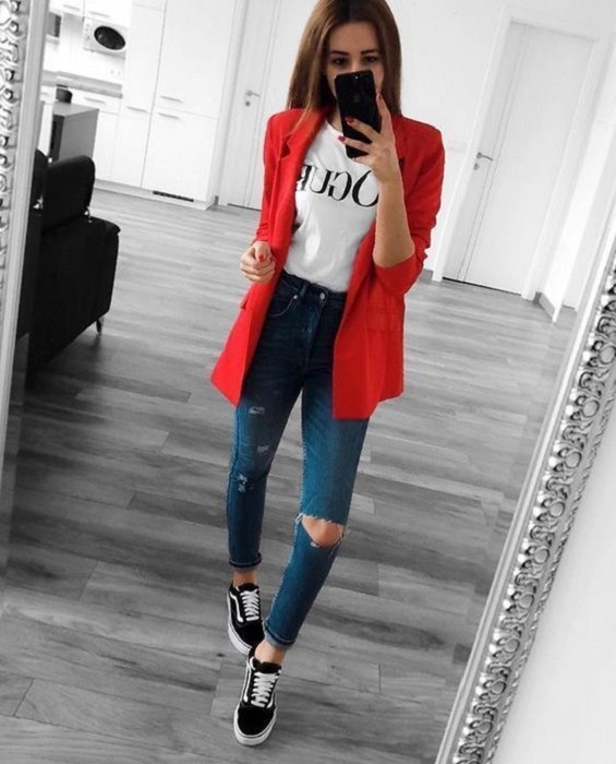 Chica usando blazer de color rojos, con blusa blanca y jeans rasgados denim y vans