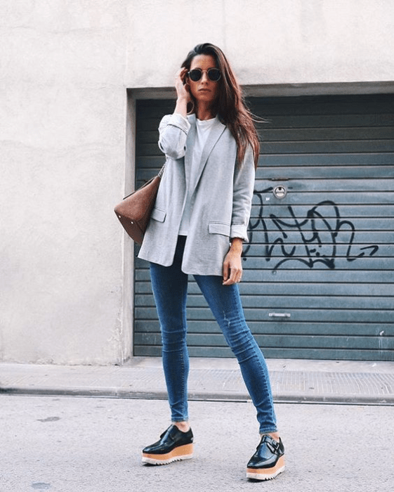 Chica usando blazer de color gris claro, y blusa blanca, jeans denim y zapatos de plataforma