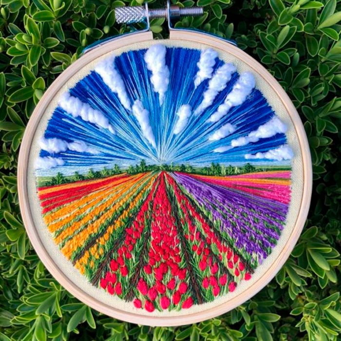 Bordado en aro hecho a mano de un campo de tulipanes de diferentes colores y un cielo despejado