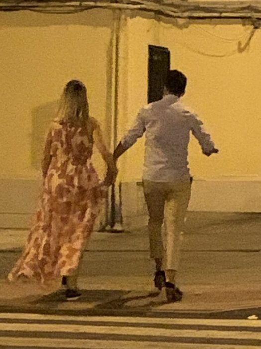 Chica y chica caminando por la calle mientras él usa los tacones de ella