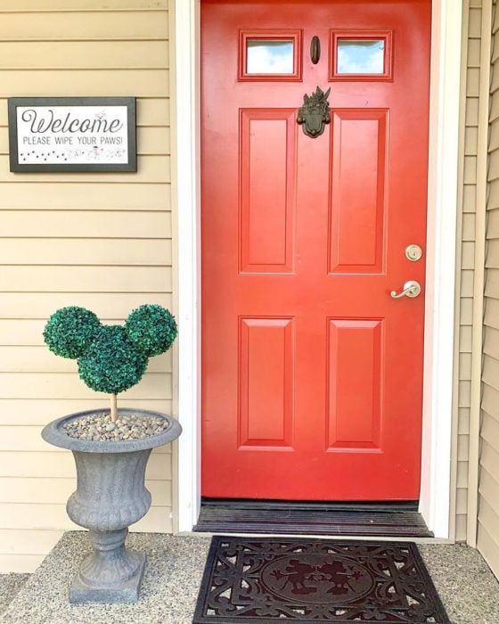 Puerta de entrada al hogar en color rojo con un arbusto en forma de Mickey Mouse