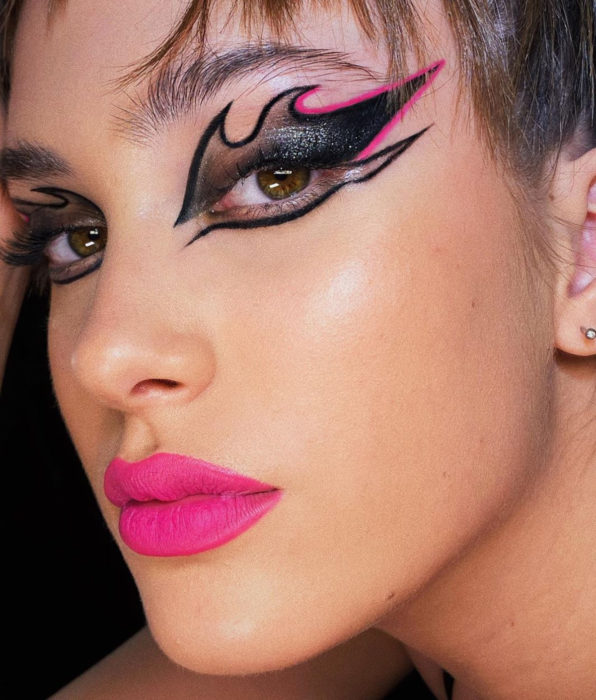 Chica morena de ojos café y verde, con maquillaje de fiesta, delineado de llamas, negro con rosa fucsia, labial rosa mexicano