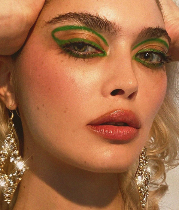 Chica con pecas, ceja poblada, ojos verdes, delineado gráfico color verde, labios rosas