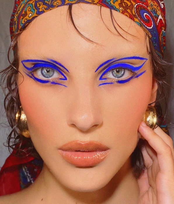 Chica de ojos azules, maquillaje para fiesta, delineado gráfico azul eléctrico, labios nude