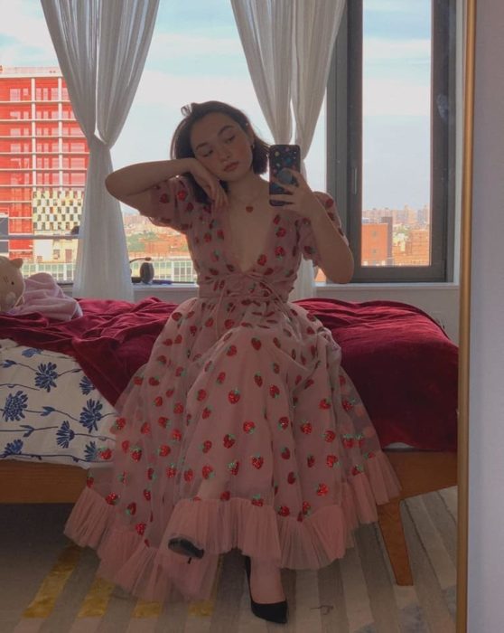 Chica tomándose selfie sentada con vestido de fresas