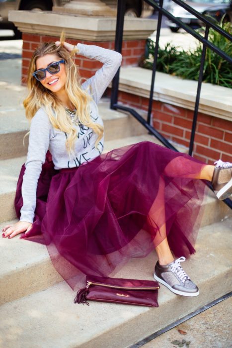 Chica usando falda de tul color vino y camisa de mezclilla y tenis plata