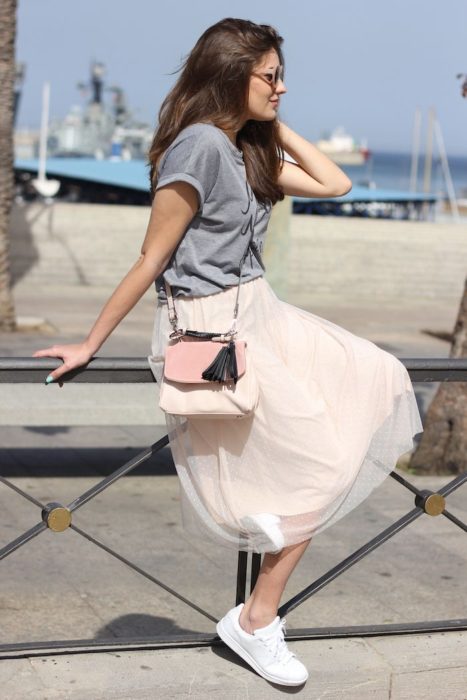 Chica usando falda de tul color beige y blusa gris y tenis blancos