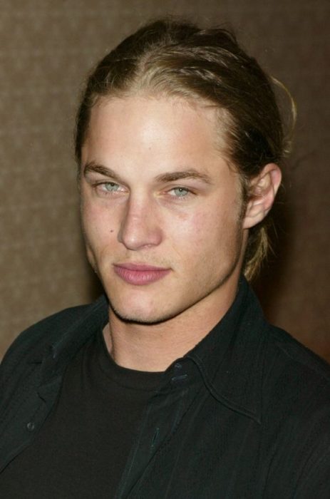 Travis Fimmel con cabello largo sujetado en una coleta