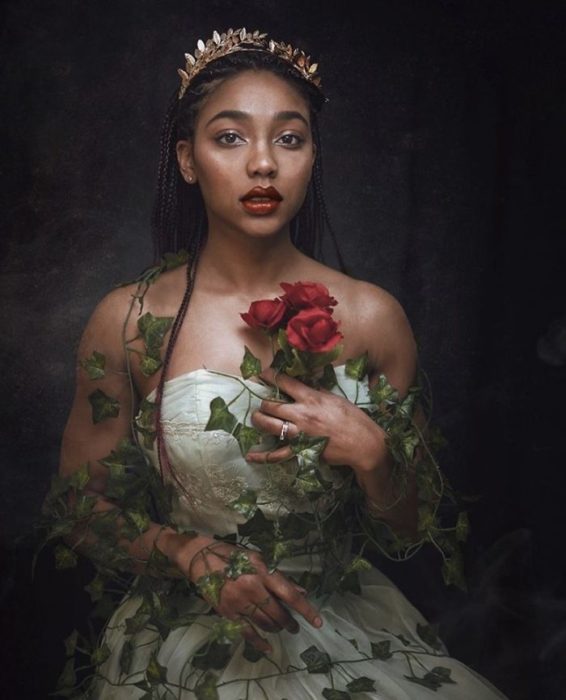 Chica negra con tiara y velo en la cabeza con vestido blanco y sosteniendo una rosa roja