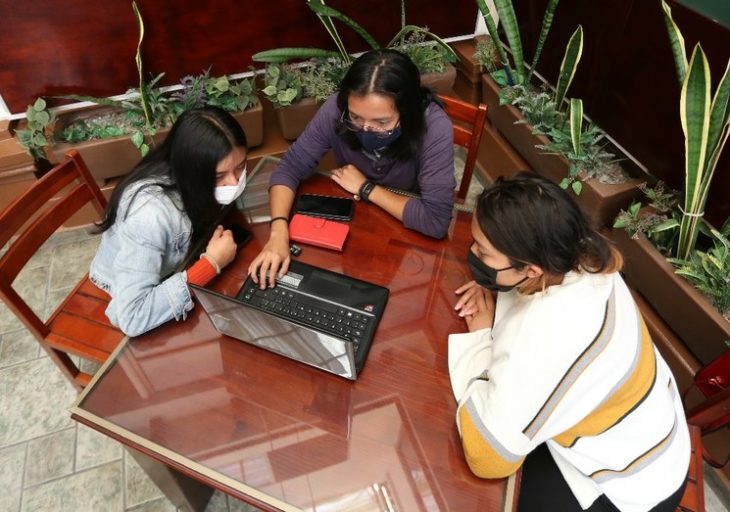 Chicas sentadas en sillas y con lapton tomando clases en línea