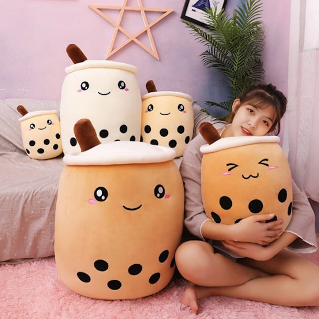 Chica abrazando una colección de almohadas en forma de vaso de café con leche