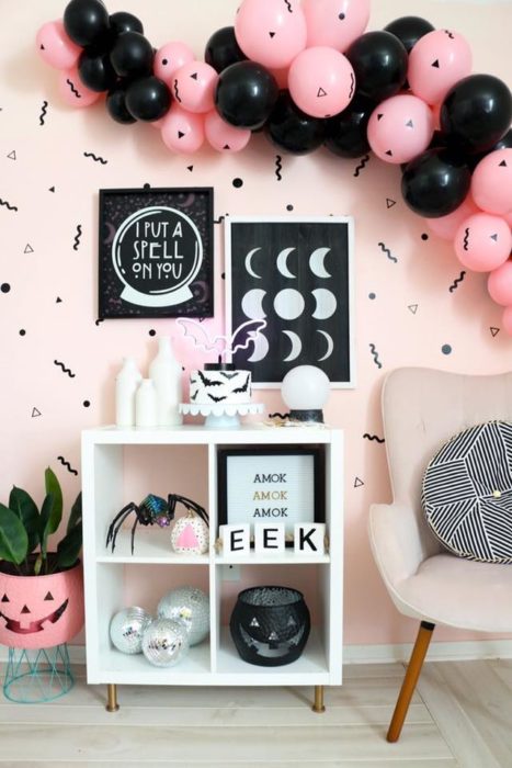 Habitación con pared rosa y detalles negros con muebles blanco y globos rosas y negros para Halloween