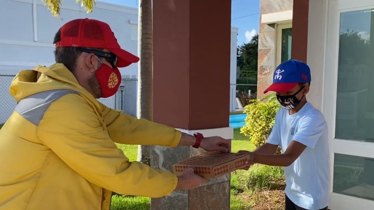 Maestro Pedro Rodríguez disfrazado como repartidor de pizza, visitando a un exalumno de primaria