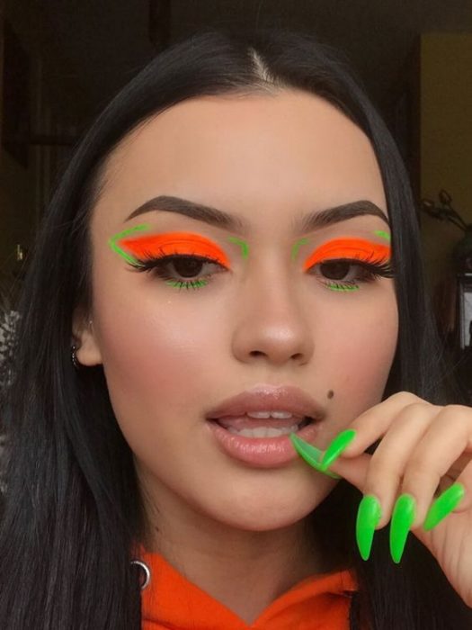 Chica morena clara con melena lisa y corta con maquillaje de ojos naranja con verde neón y labios nude