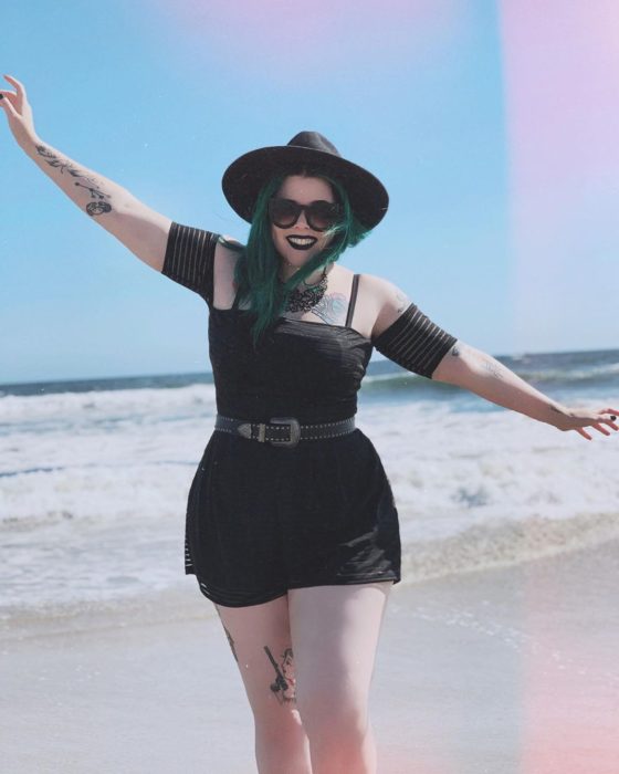 Chica usando un total black look de short y top off the shoulder, además de sombrero