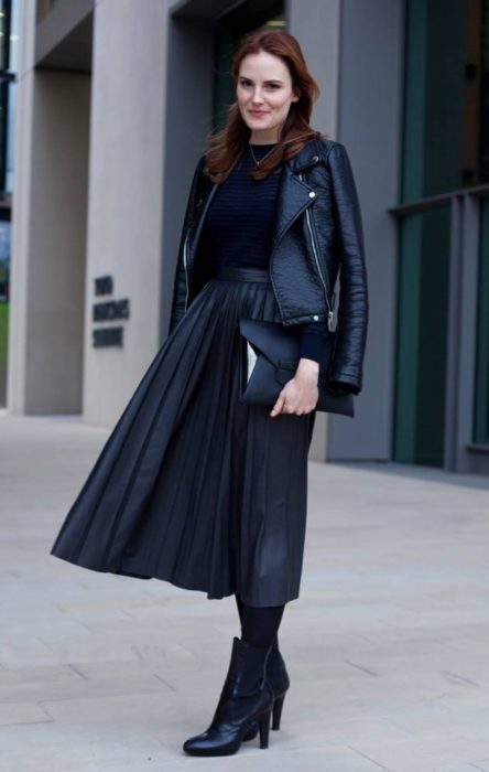 Chica usando una maxifalda negra, botines con medias del mismo color, una blusa y chaqueta de cuero del mismo color