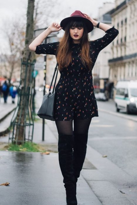 Chica usando un total black look de medias, vestido de manga 3/4, corto y sombrero