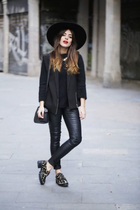 Chica usando un total black look de leggins, blusa y chaqueta de cuero, sombrero y zapatos mocasin con estampado de animal print