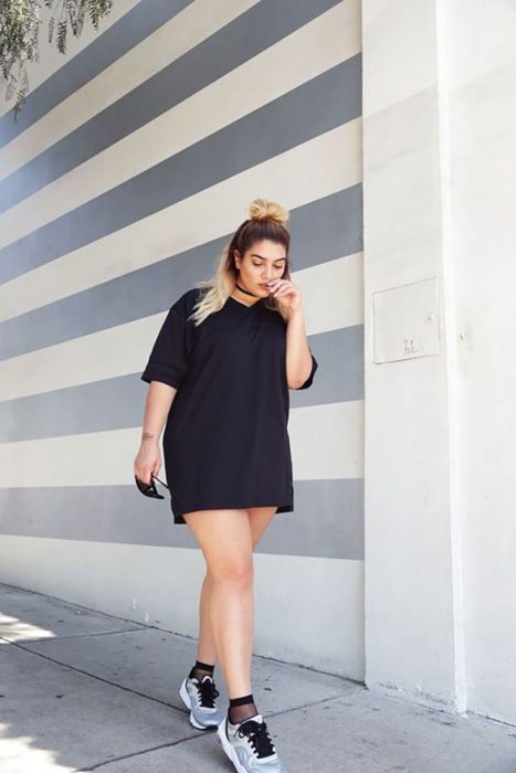 Chica usando un total black look de un vestido oversized corto de manga corta y tenis