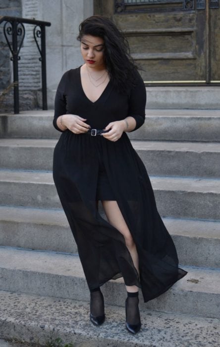 Chica usando un total black look de vestido de manga tres cuartos con abertura a un lado y botines