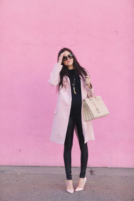 Chica usando outfit con detalles en baby pink en abrigo y bluza y leggins negros