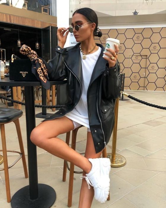 Chica usando chaqueta de cuero negra con playera oversized y tenis blancos