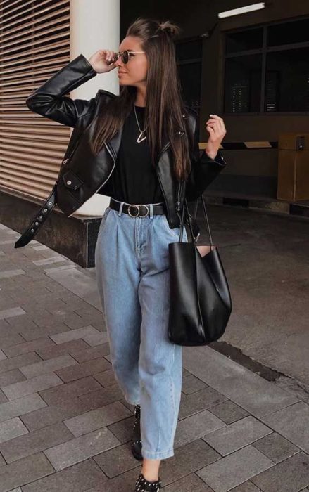 Chica usando chaqueta de cuero negra con mom jeans y blusa negra