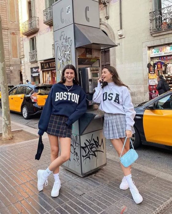 Chicas usando falda con estampado a cuadros y sudaderas holgadas