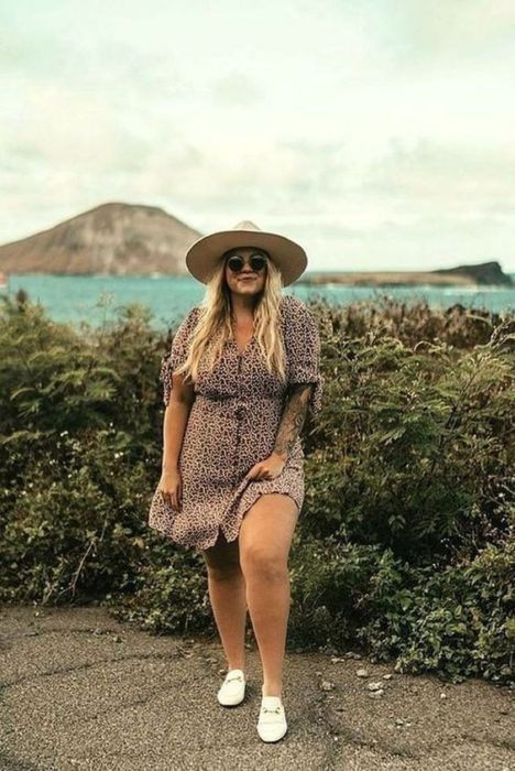 Chica usando outfit veraniego de vestido color café con botones, tenis blancos, lentes oscuros y sombrero de paja