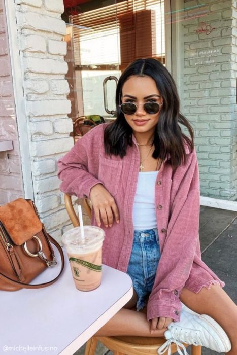 Chica usando outfit con detalles en baby pink en chaqueta, y shorts denim y blusa y tenis blancos