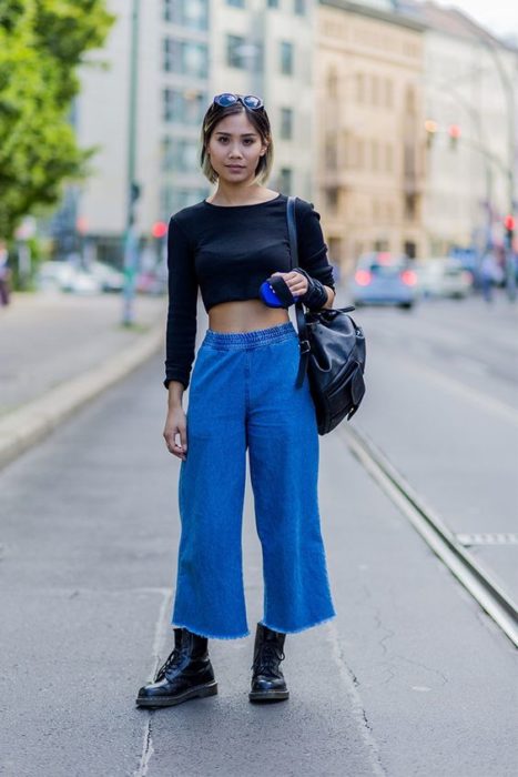 Chica delgada asiática con top de manga larga color negro y culotte azul marino con botas dr. martens 