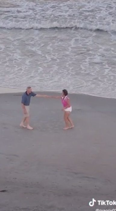 Pareja de ancianos baila alegremente en la playa