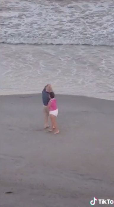 Pareja de ancianos baila alegremente en la playa