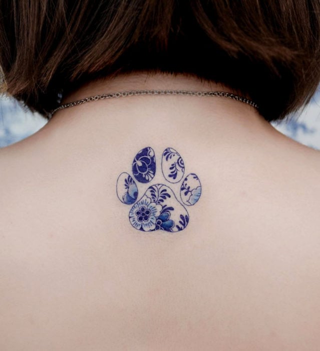 Tatuaje pequeño estilo japonés de tinta azul de huella de perro con flores en la espalda