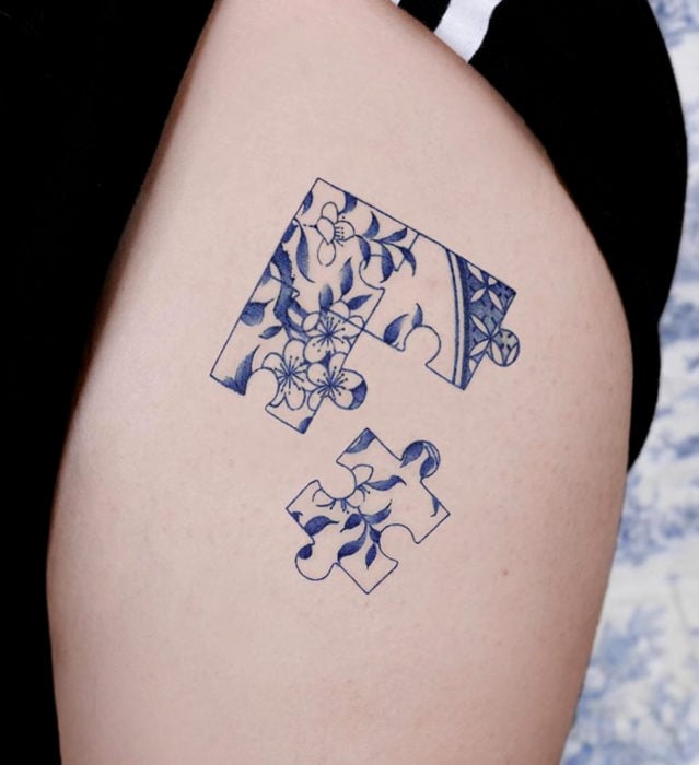 Tatuaje pequeño estilo japonés de tinta azul de piezas de rompecabezas de flores en la pierna