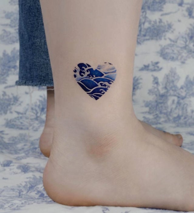Tatuaje pequeño estilo japonés de tinta azul de corazón con olas de mar en el tobillo